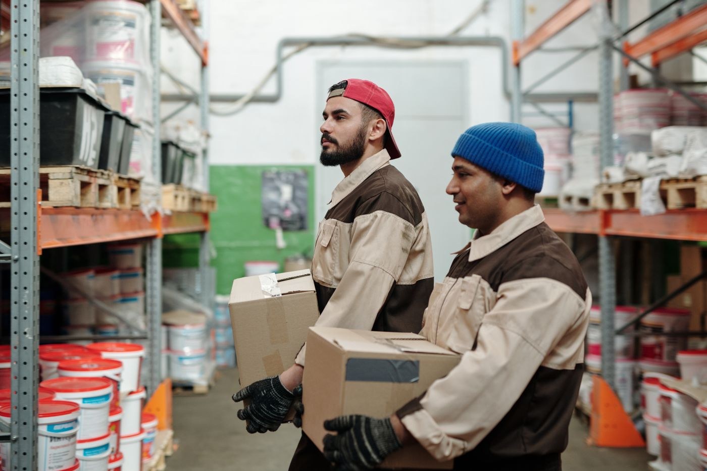 Two warehouse workers carrying cardboard cartons